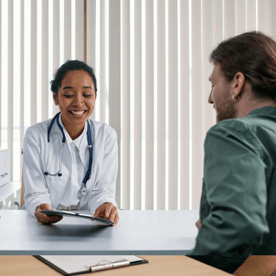 A doctor smiling and looking down at her clipboard